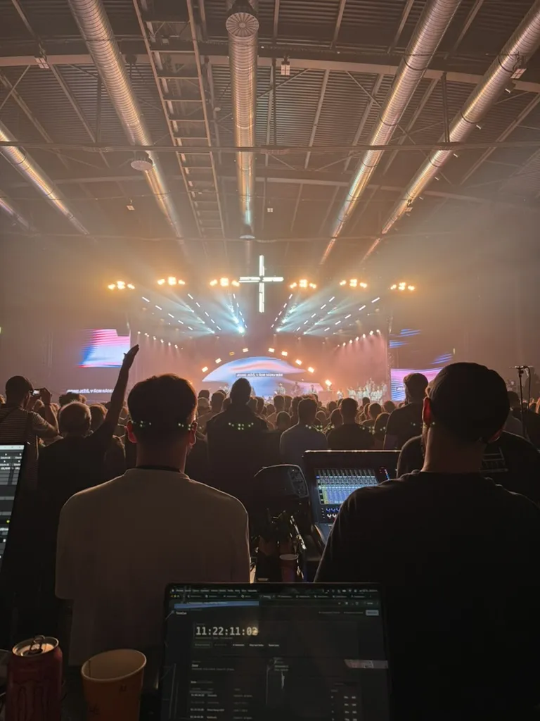 Front of house at a GODZONE tour 2026 show: a packed arena in front of the stage, with TimeCue running on a laptop at the desk